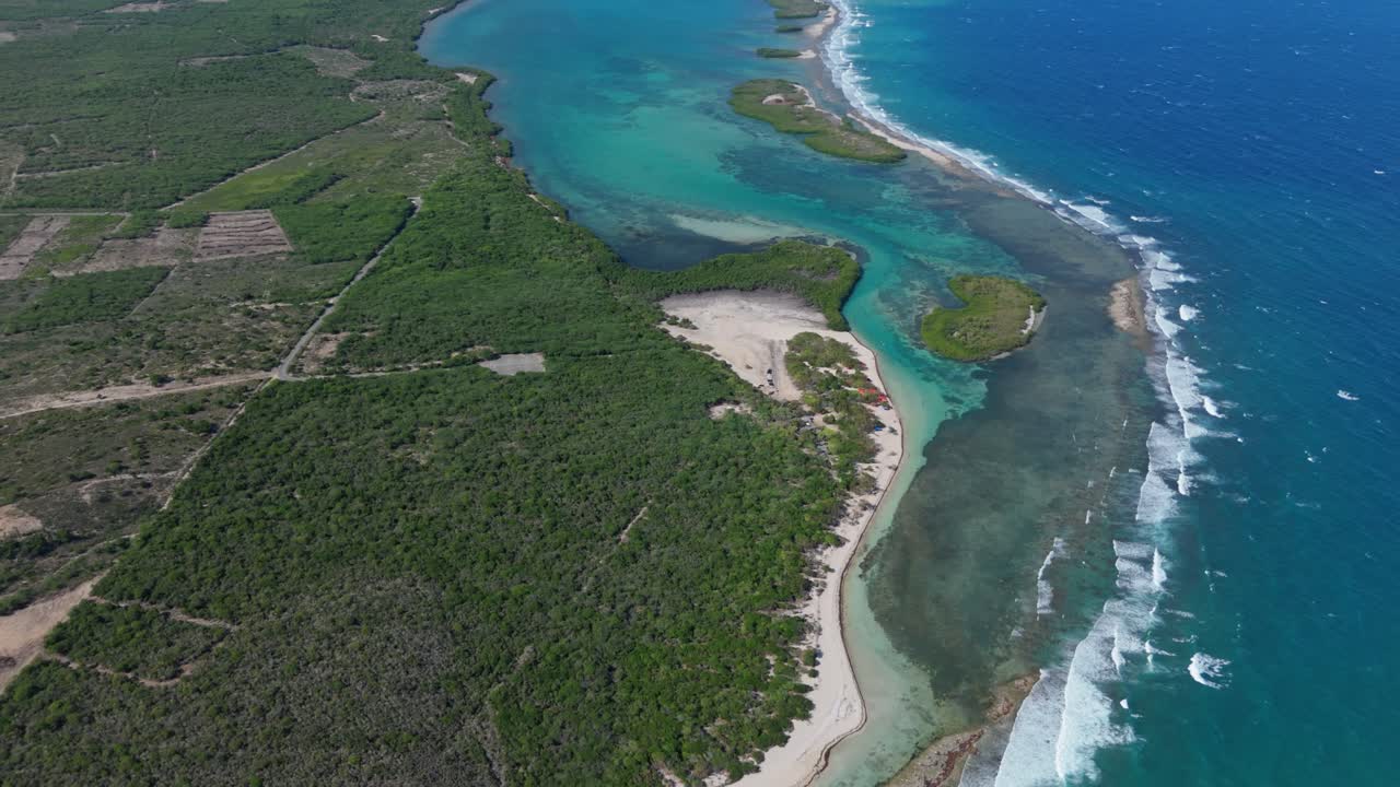 Aerial top down of blue turquoise lagoon of Playa Caobita, Azua. green islands with Caribbean sea waves.