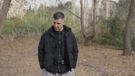 a man hangs his head, contemplating life as he walks alone through a secluded nature trail