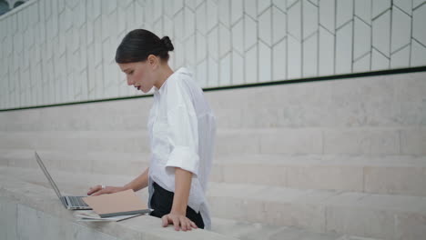 Woman-writer-typing-outdoors.-Girl-writing-text-on-laptop-using-notes-vertical.