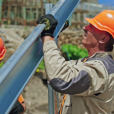 solar panel technicians install metal frame. workers in orange helmets making metal basis for solar system on the field. close-up.