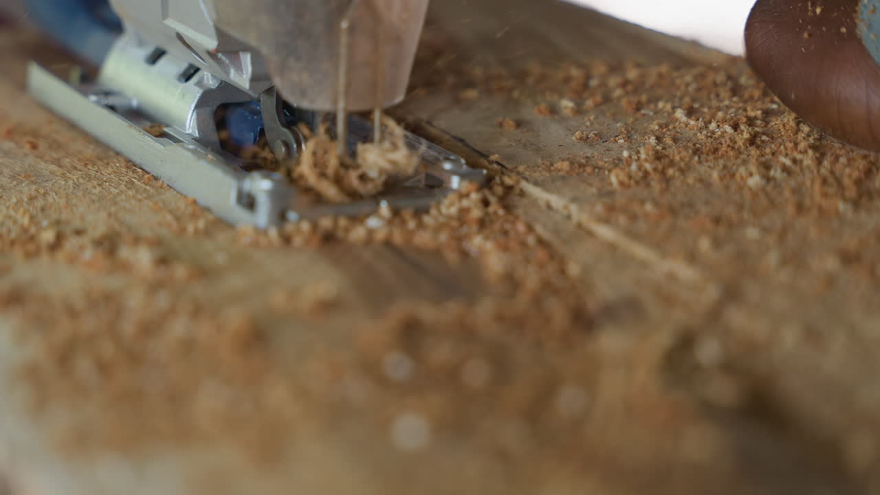 Closeup jigsaw cutting wood plank, fine sawdust scattering, focused hand guiding tool, rough grain texture, precise shallow groove, intimate workshop atmosphere, carpentry technique on display