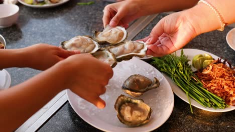 hands preparing oysters with garnishes and sauces