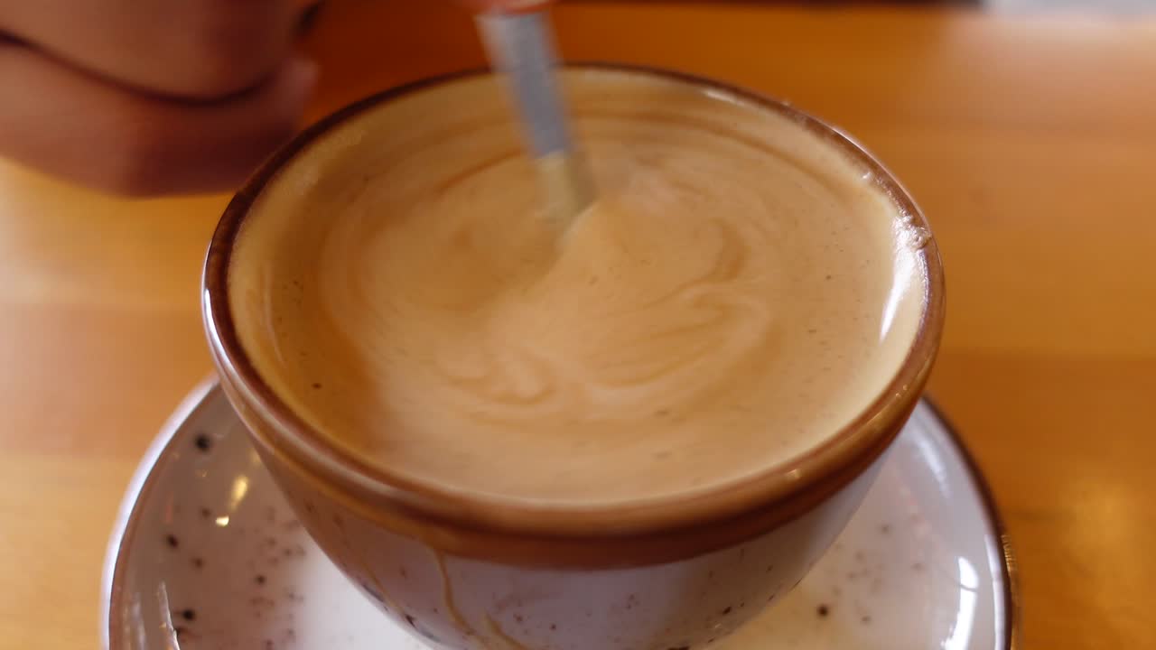 Close-up of a cup of coffee being stirred with a spoon