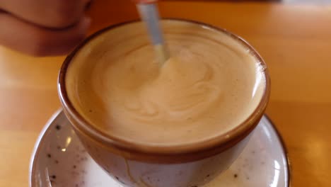 close-up of a cup of coffee being stirred with a spoon