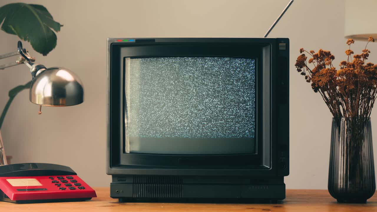 TV retrò, televisione vintage. In un'ambientazione nostalgica, un televisore retrò mostra grana sullo schermo, dispositivo per una spaventosa notte di Halloween, ottimo per chroma key e green screen. Filmato 4K di alta qualità.