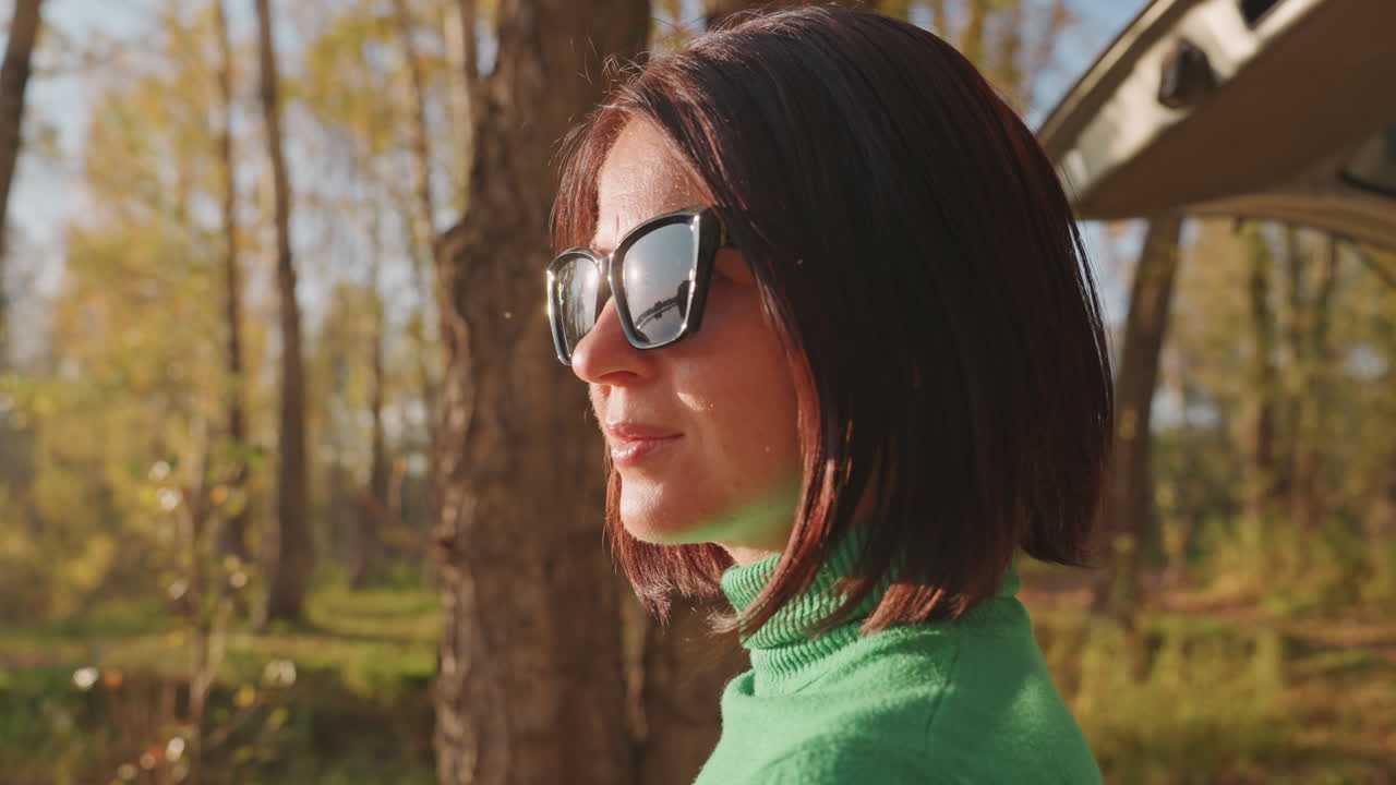 Donna trova un rifugio di pace. Donna si rilassa da sola tra gli alberi autunnali. Scena mattutina serena con donna in maglione verde scuro. Donna solitaria si gode una mattinata tranquilla in un ambiente forestale autunnale.