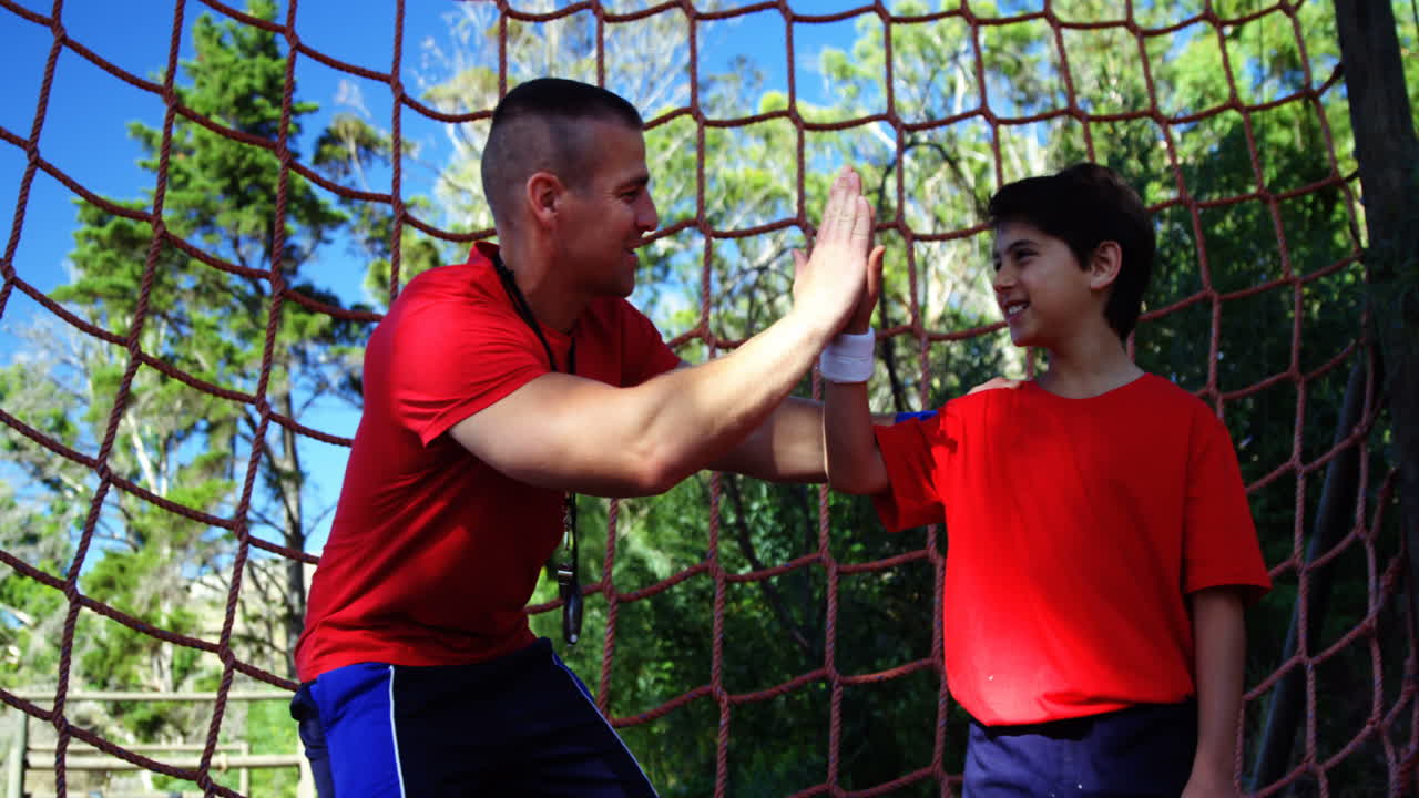 Trainer giving high five to boy in the boot camp
