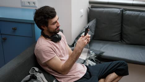 hombre en el sofá desplazándose por el teléfono inteligente en casa