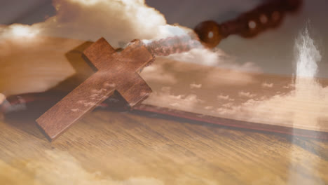 animation of christian cross over rosary beads, clouds with wooden surface in the background