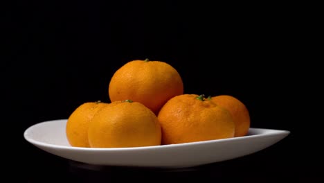 primer plano de mandarinas girando en un tocadiscos en un plato sobre un fondo negro