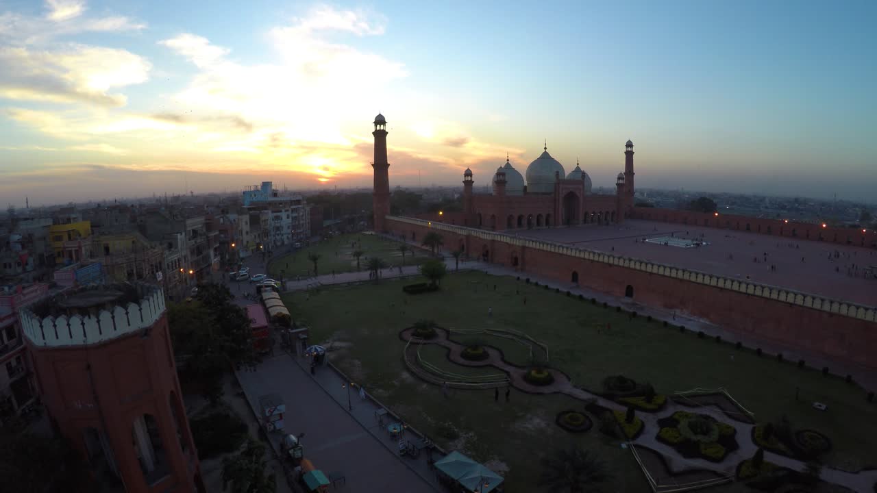 Riprese aeree della Moschea Badshahi a Lahore, Pakistan, catturate al tramonto. Viene evidenziata l'architettura di epoca Moghul con grandi cupole, alti minareti e un vasto cortile.