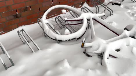 Fallen-Bike-On-Rack-Covered-With-Snow-At-Wintertime