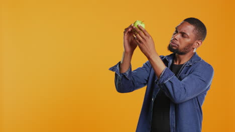 joven inspeccionando una manzana verde recién cosechada en el estudio