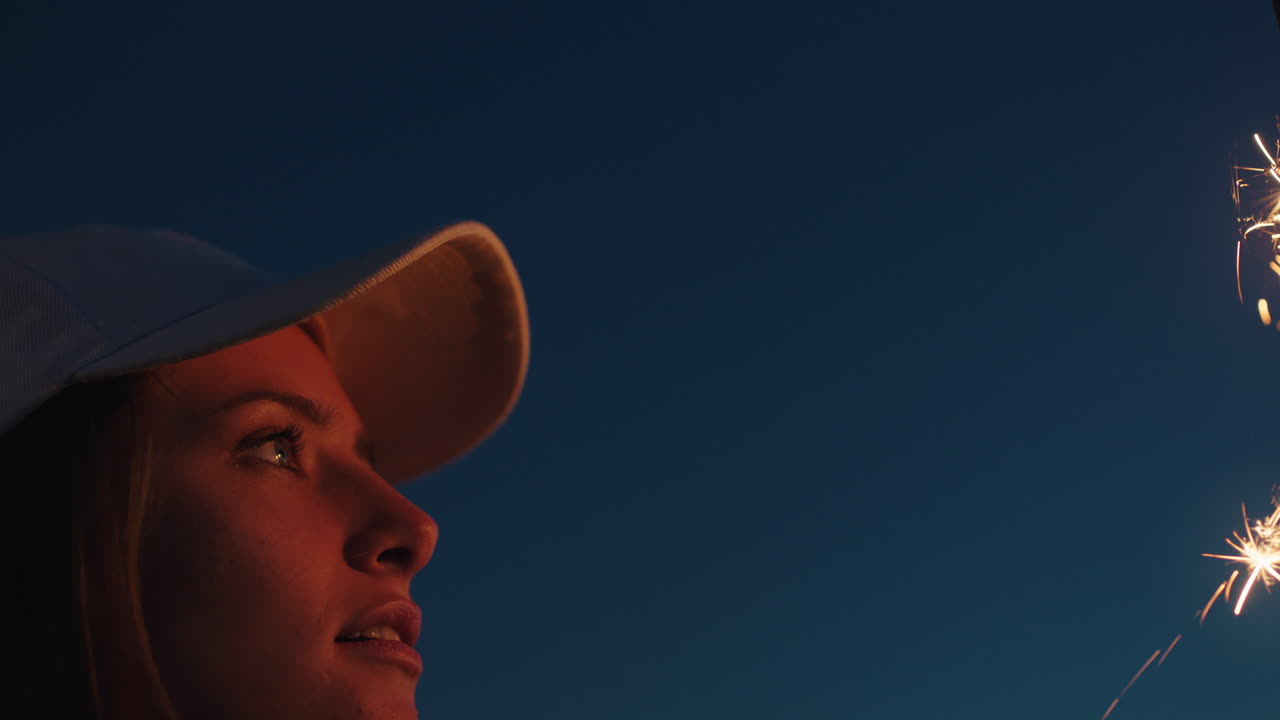 mujer jugando con bengalas en la playa al atardecer disfrutando de la celebración de nochevieja mirando chispas de fuegos artificiales niña celebrando el día de la independencia