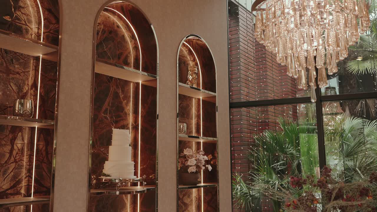 Elegante interior para bodas con tarta, arreglos florales e iluminación ambiental cálida