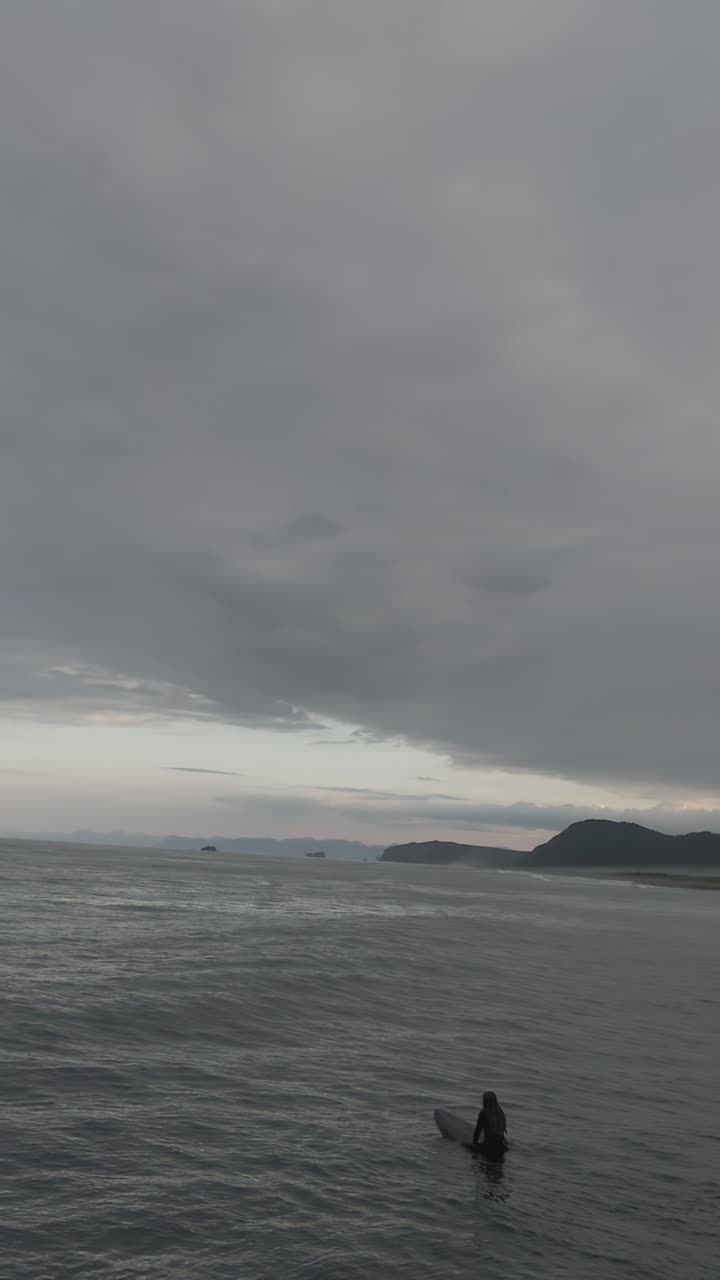 Surfers in a grey, cloudy ocean landscape