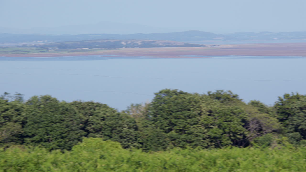 Bidikan panning lebar dari kanan ke kiri Morecambe saat air pasang di dekat Ulverston di Circle, Lingkaran Batu Birkrigg