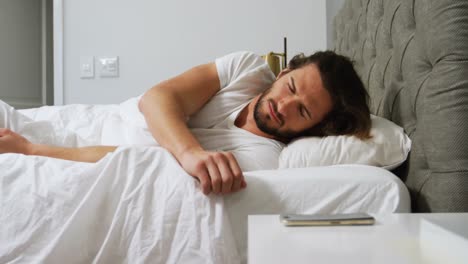 Man-checking-his-mobile-phone-in-bedroom