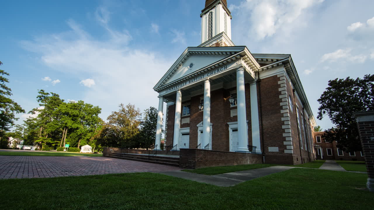 Motion time lapse tilting up to a church as clouds move by in the sky above