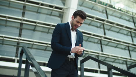 cheerful man enjoying victory in stylish suit outside