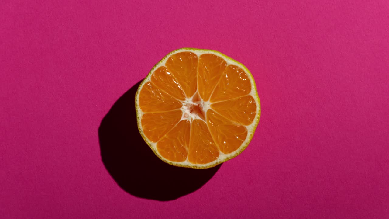 mitades de mandarina frescas con una fuerte sombra en un fondo amarillo, rosa y azul. animación de movimiento de parada