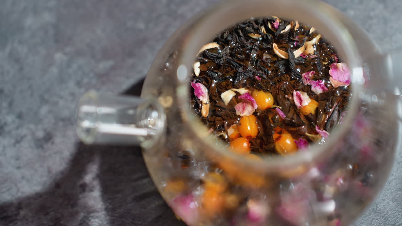 Colorful Floral Tea Display, Artisan Style Loose Leaf Tea With Flowers And Berries In Clear Teapot, Aesthetic View Of Herbal Loose Leaf Tea Adorned With Roses And Berries Inside Glass Teapot