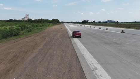 a cinematic aerial shot of a car stopping in along a bustling highway, with the impressive sight of an emergency landing runway constructed on nh 16 at korisapadu area of the chennai-vijayawada