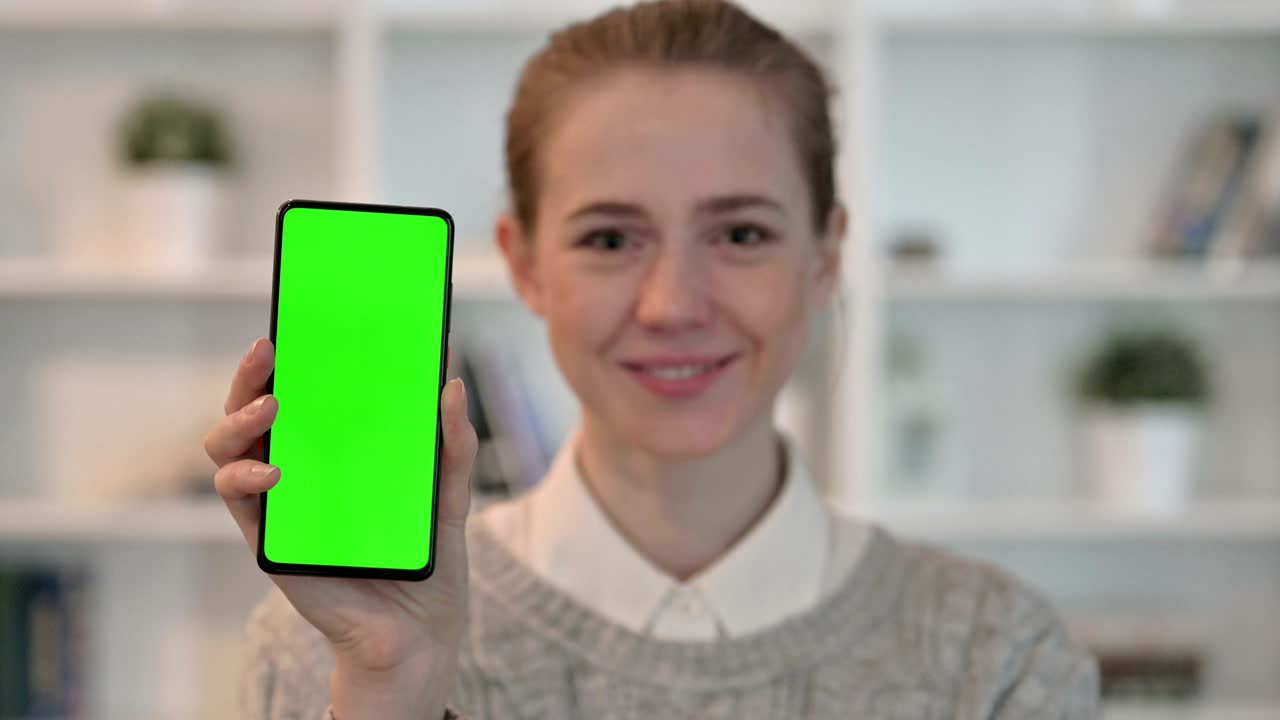 mujer joven mostrando un teléfono inteligente con pantalla de tecla cromada