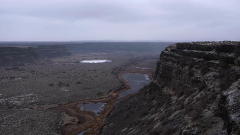 Winter-footage-of-dramatic-basalt-cliffs-overlooking-desert-scablands,-pans-right-to-left