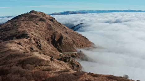 Carretera-De-Montaña-Sinuosa-Sobre-Las-Nubes-Con-Un-Cielo-Azul-Claro