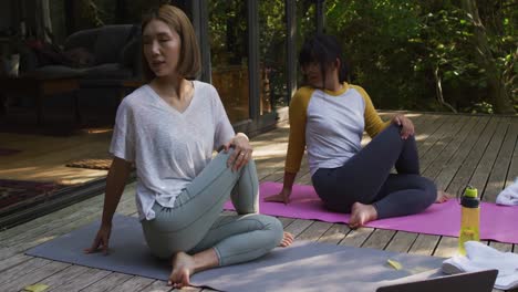 Asian-mother-and-daughter-practicing-yoga-outdoors-in-garden