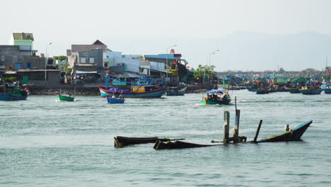 Boats-sailing-on-Phan-ri-cua-coast,-old-sunken-fisherman-boat-in-foreground