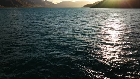 Los-Rayos-Del-Sol-Se-Reflejan-En-Las-Brillantes-Aguas-Del-Lago-Wakatipu-Con-Siluetas-De-Montañas