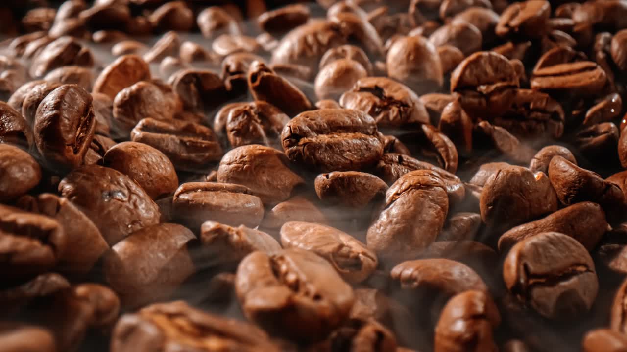 Close up of seeds of coffee. Fragrant coffee beans are roasted smoke comes from coffee beans.