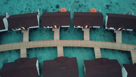 drone top down video of a tropical resort in the maldives, blue lagoon, sunny weather, turquoise shallow water, water villas, island wooden road, 4k