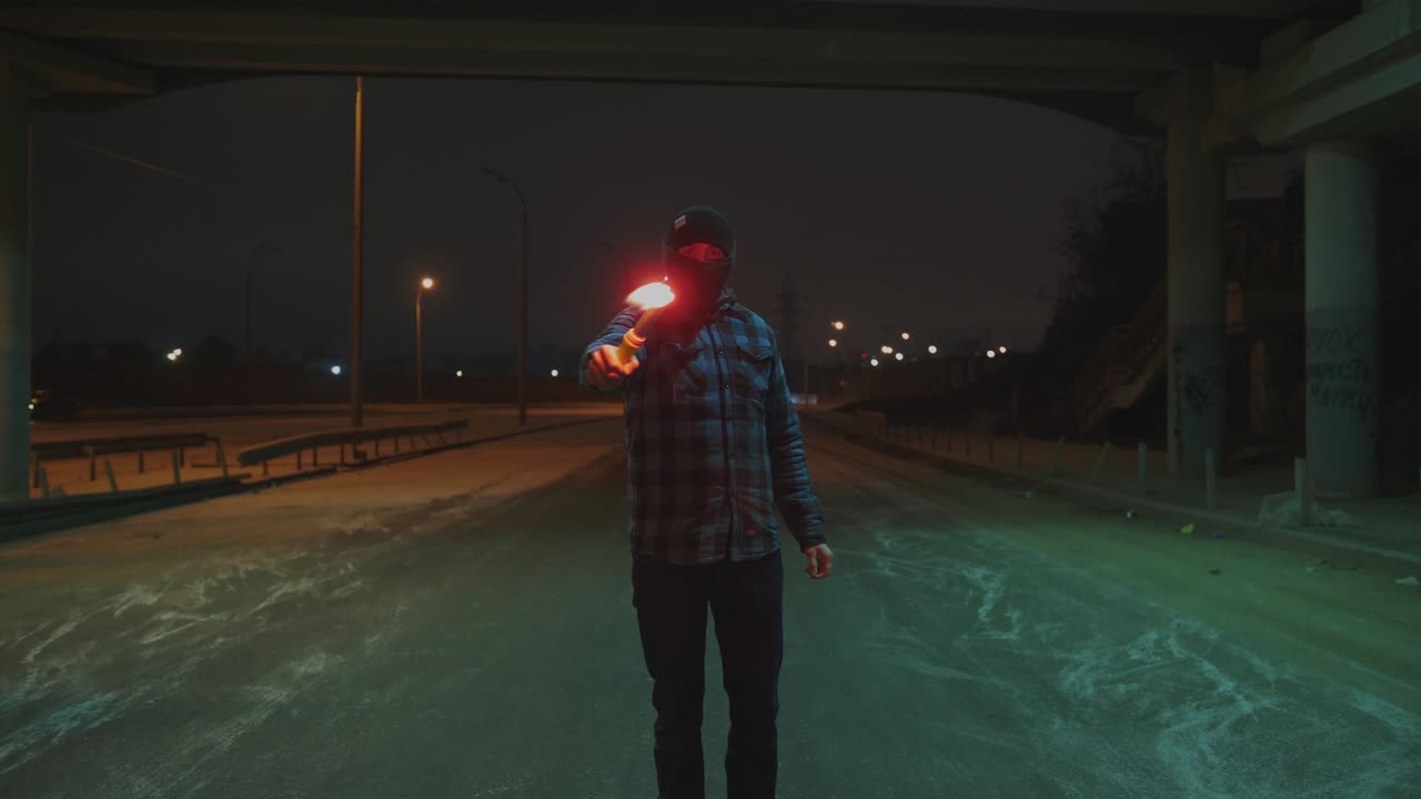 밤에 빨간색 불타는 신호 플레어와 함께 발라클라바를 입은 남자