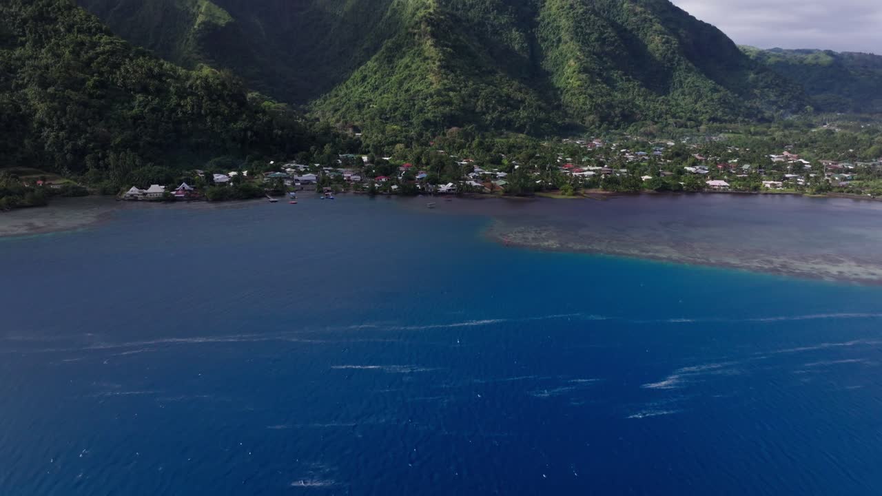 Drone video panning up revealing the coastline while also showing the turquoise waters and coral reef of Tahiti, French Polynesia
