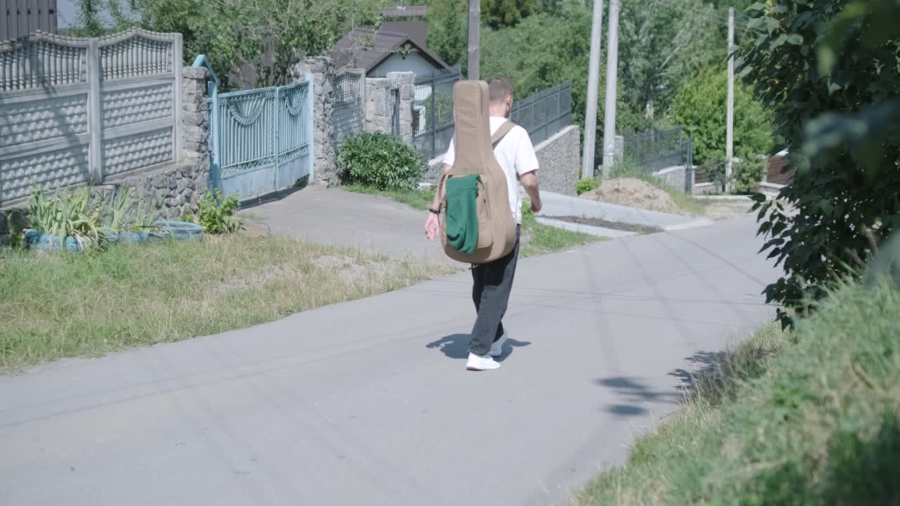 숲 근처의 거리에서 기타를 들고 는 젊은 남자