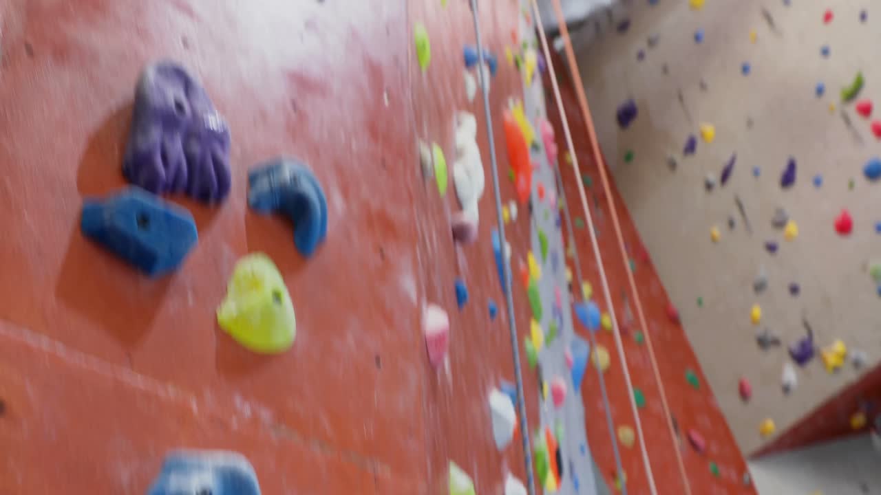Mulher tensa batendo na parede durante bouldering 4k