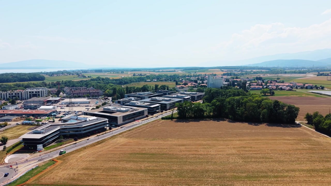 Un campo dorato si estende accanto a un parco commerciale vicino a Nyon, in Svizzera, ripreso da un drone in panoramica