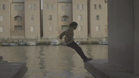 person jumping and sitting by a canal in venice