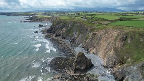 Rough-incoming-tides-at-tankards-town-on-The-Copper-Coast-Waterford-with-storm-clouds-approaching-from-the-Comeragh-Mountains-on-a-blustery-summer-day