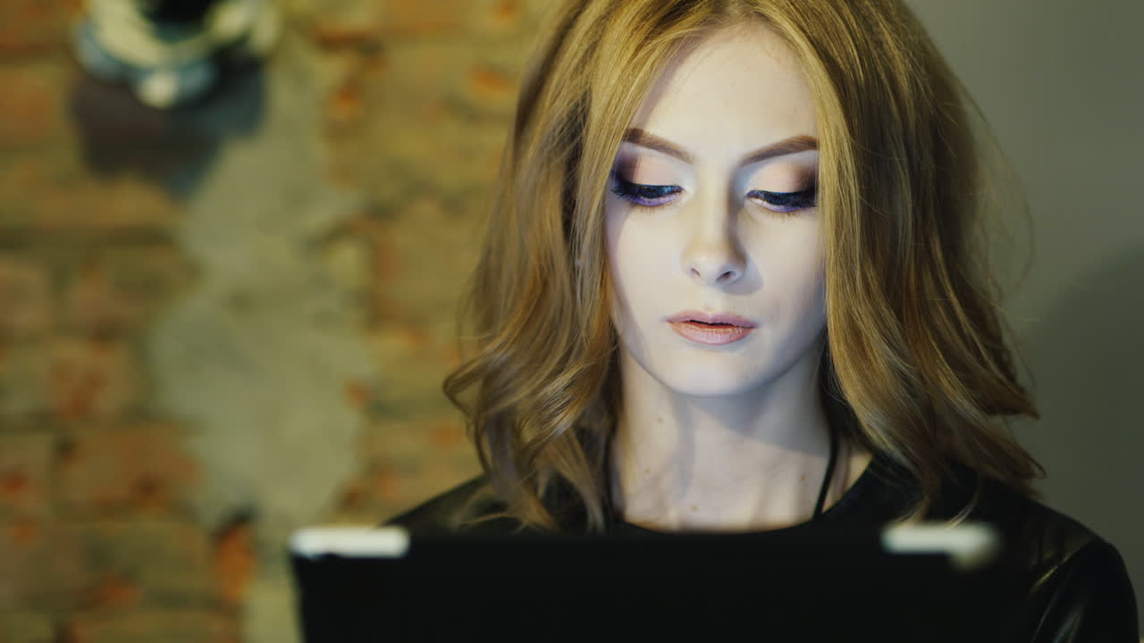 женщина 20-25 лет пользуется планшетом в кафе с длинными волосами модельной внешности