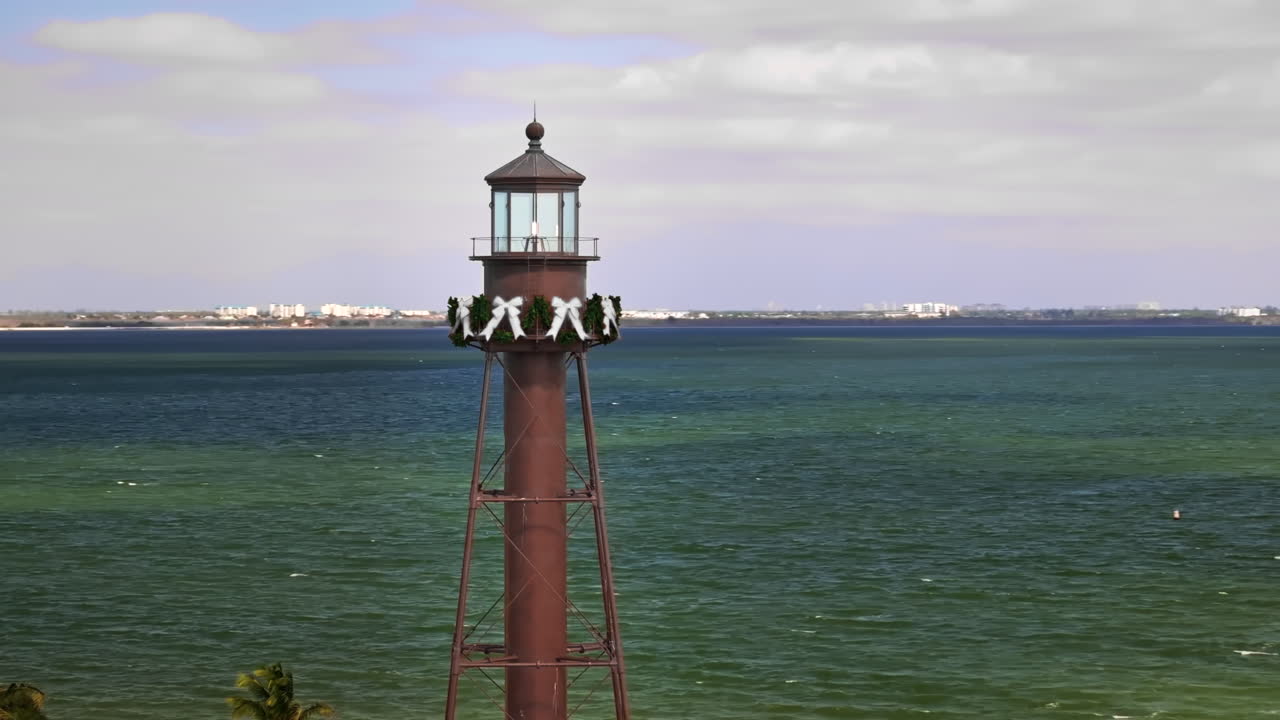 Una ripresa aerea cinematografica da 70mm con drone che orbita attorno allo storico faro di Sanibel Island all'estremità orientale di Sanibel Island, Florida, con un luminoso litorale costiero vicino a Fort Myers
