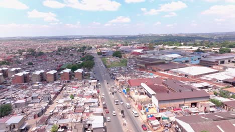 aerial panning shot over alexandra township, johannesburg, south africa, on a sunny day with scattered clouds and cars moving on main road
