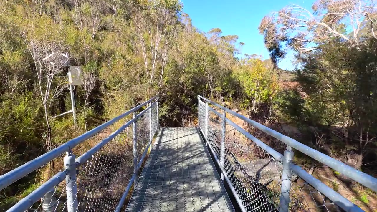Prospettiva in prima persona mentre si cammina su un ponte di metallo su un sentiero escursionistico a Wentworth Falls, Australia