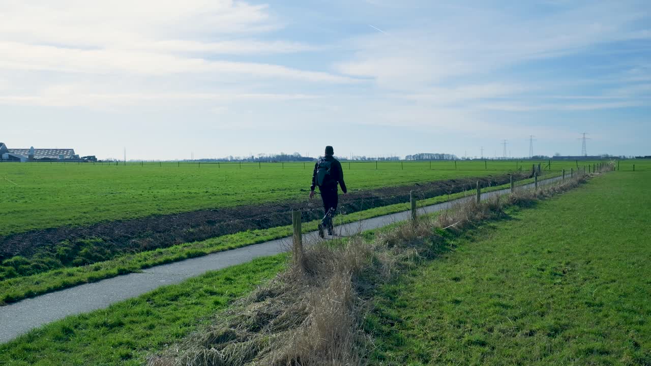 Una persona che cammina su un sentiero attraverso verdi campi rurali.