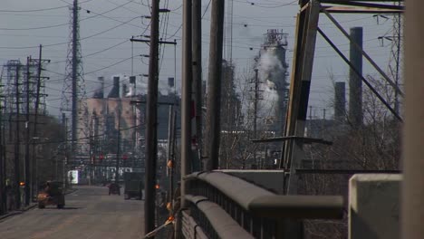 an innercity industrial area with refineries utility wires smoke and traffic