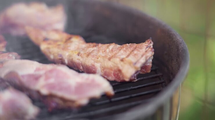 Gerak Lambat Penjepit Membalik Daging Mendesis di Atas Pemanggang BBQ Berapi dan Berasap