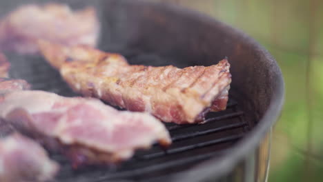 slow motion of tongs flipping sizzling meat on fiery and smokey bbq grill